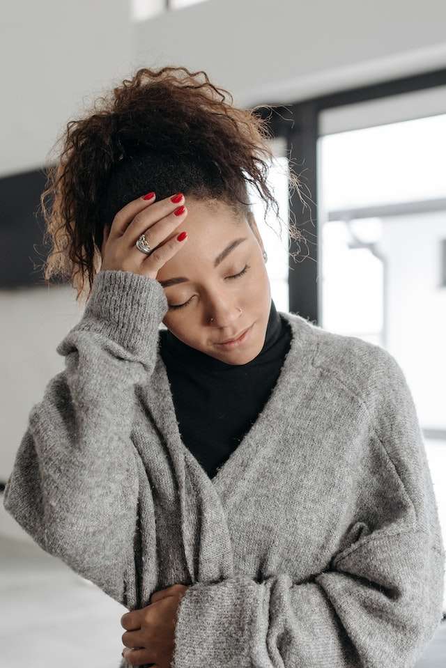 Woman sick with the flu touching her forehead